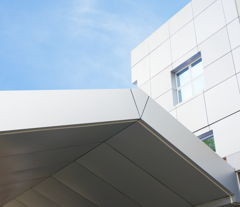 A white angular building canopy and modern exterior facade, illustrating the architectural finish provided by a standard aluminum composite panel.