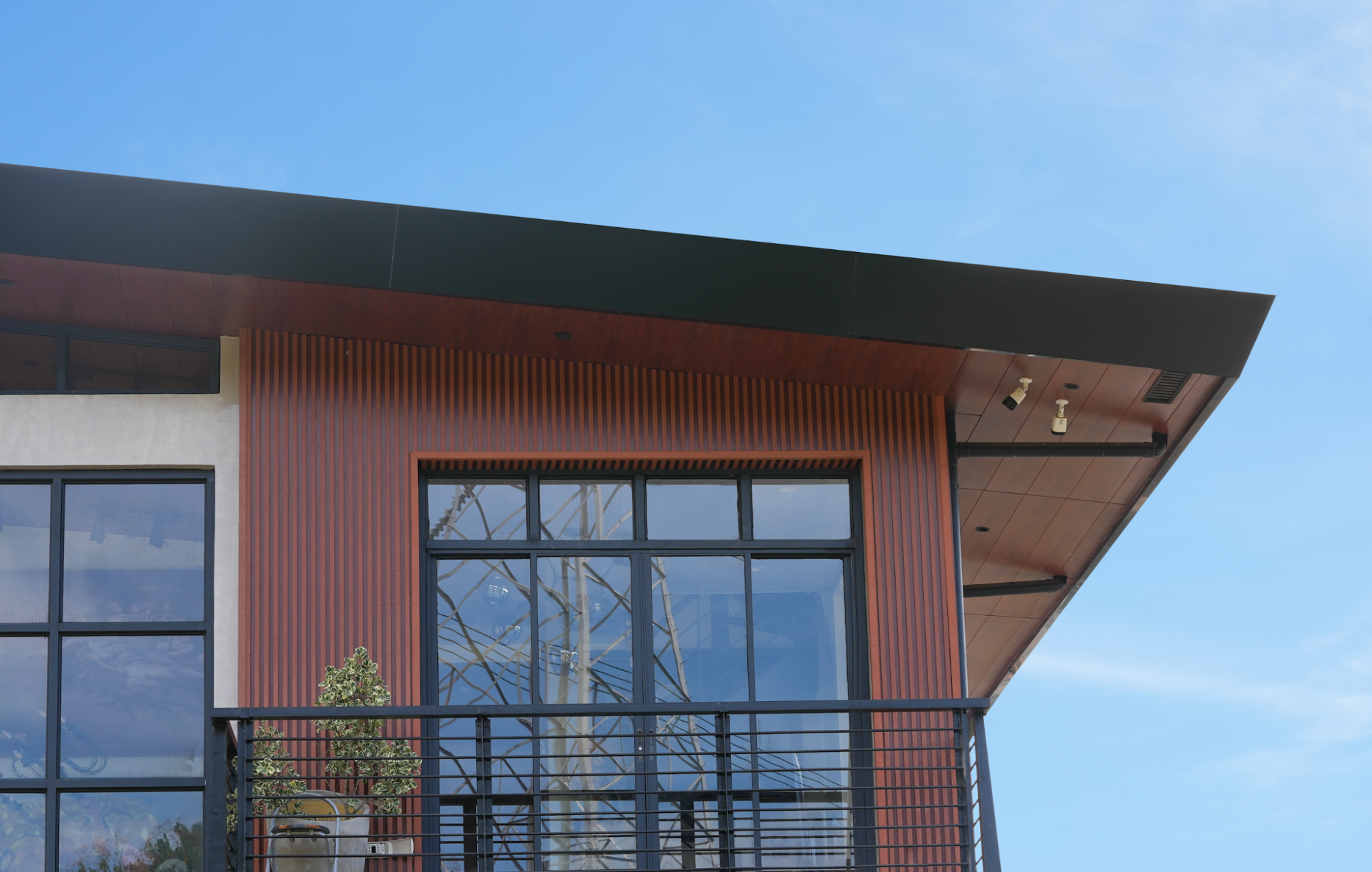 Rust-red ACP sheet cladding on a modern building facade with black roof overhang